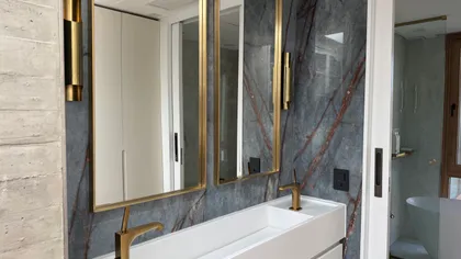 Baño moderno con lavabo doble, grifería dorada y pared de mármol — proyecto CASA MHN, por Hermann Arquitectos, en Nordelta